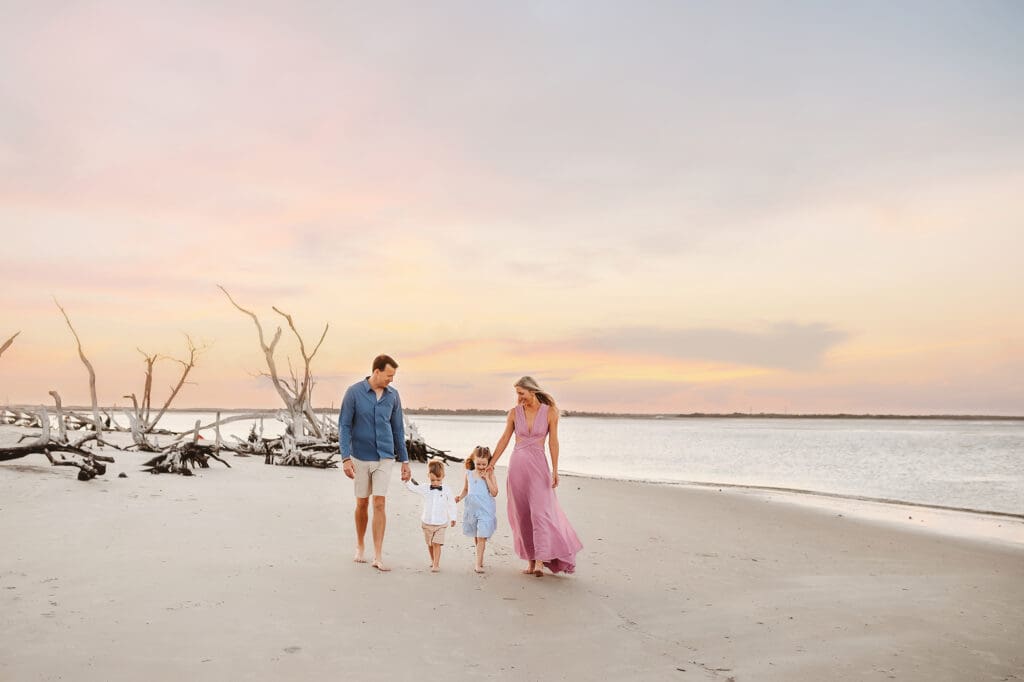 Parents walk along the beach with their children during Family Pictures on Folly Beach, South Carolina.