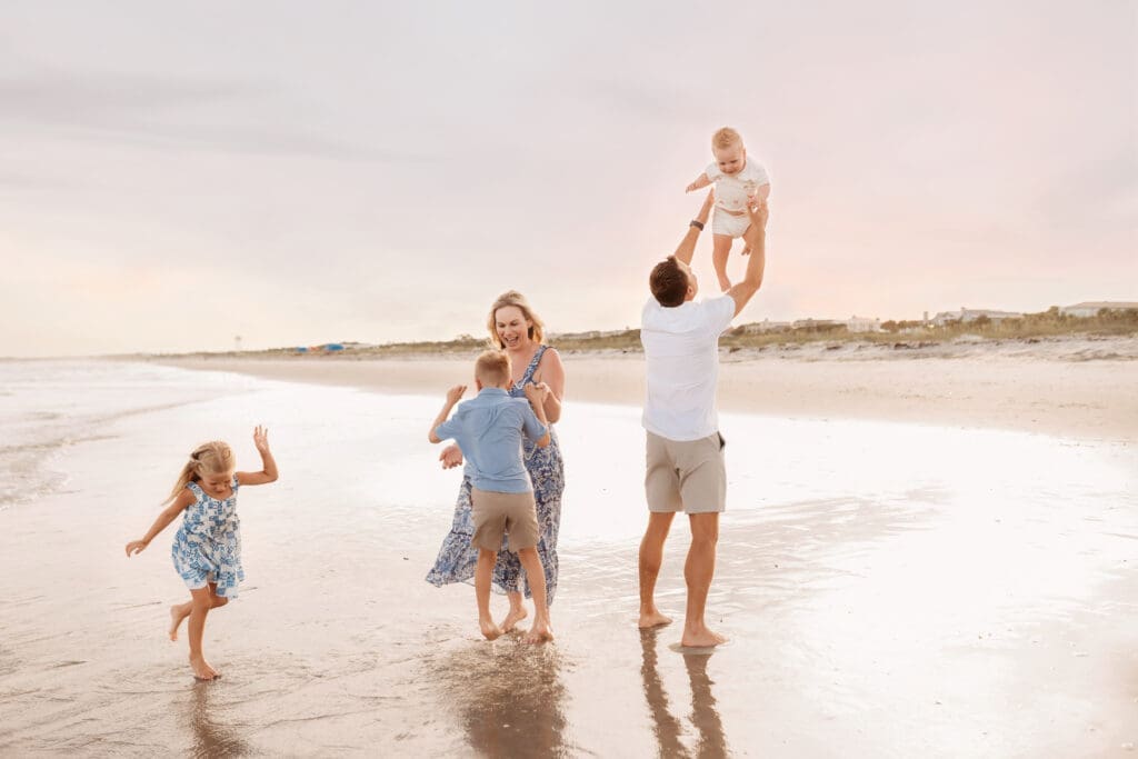 Family plays together on the beach for summer, sunset beach mini sessions on Folly Beach with Holy City Family Photography after searching for Charleston Mini Sessions.