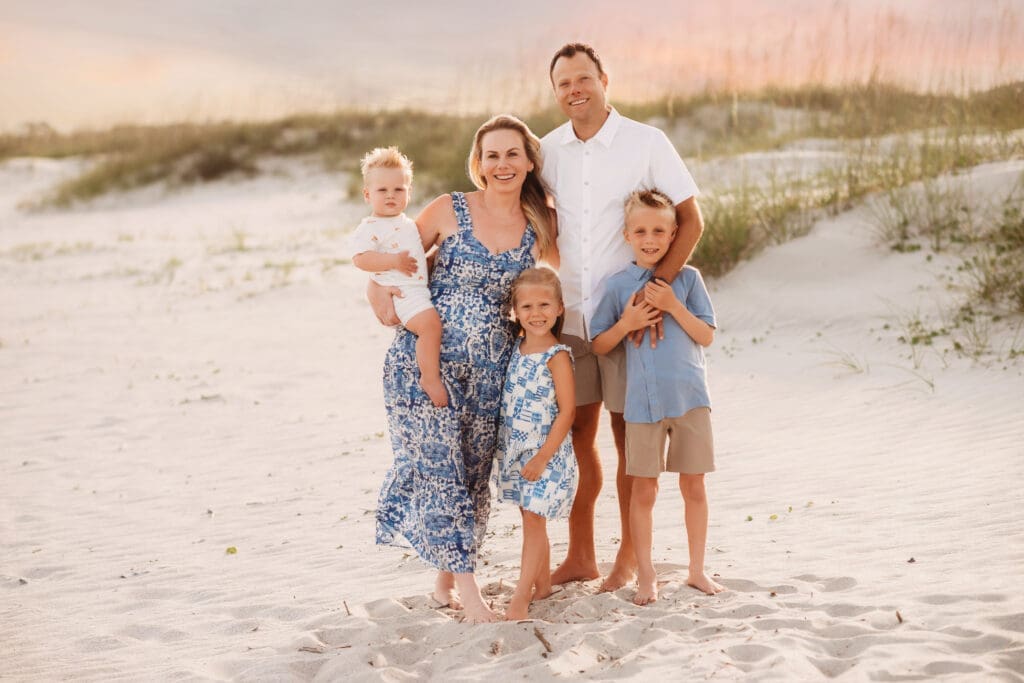 Family poses together for summer, sunset beach mini sessions on Folly Beach with Holy City Family Photography after searching for Charleston Mini Sessions.