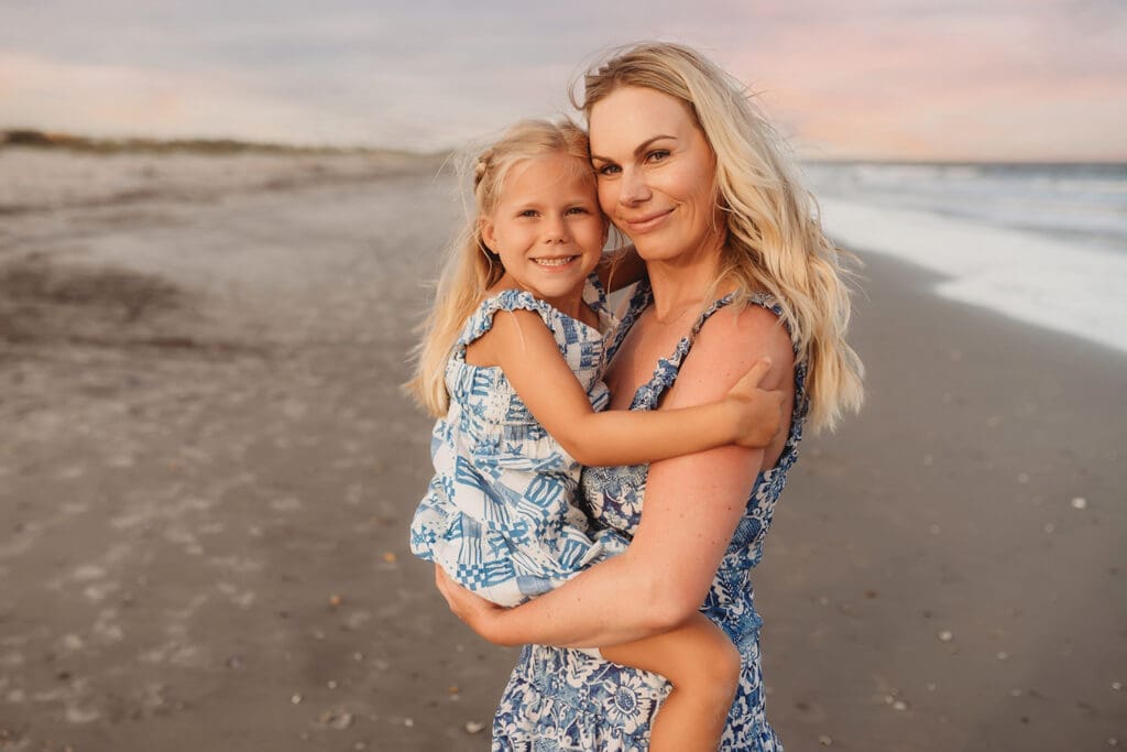 Mother embraces her daughter on Isle of Palms Beach during Family Portrait Session with, Holy City Family Photography in Charleston, SC.