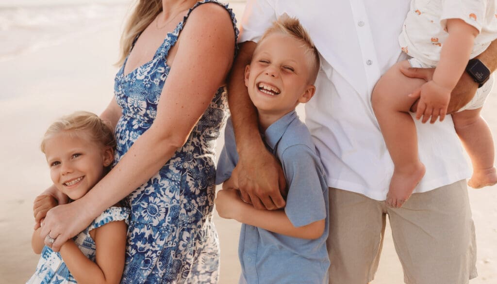 Family poses together for summer, sunset beach mini sessions on Folly Beach with Holy City Family Photography after searching for Charleston Mini Sessions.